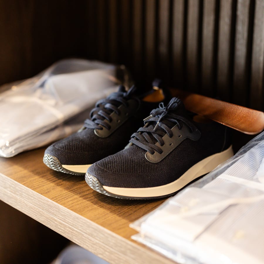 LECIANO Showroom – marineblauer Sneaker neben frisch verpackten Hemden
